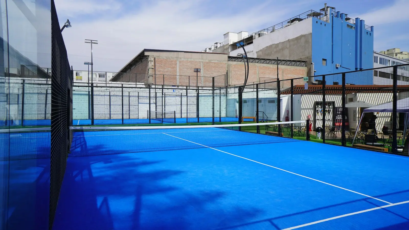 Outdoor padel court with blue artificial turf, glass walls and a net