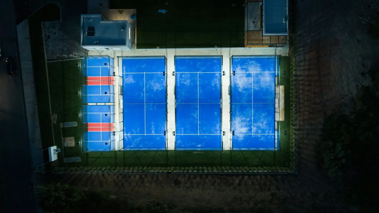 Top-down night view of four lit padel courts
