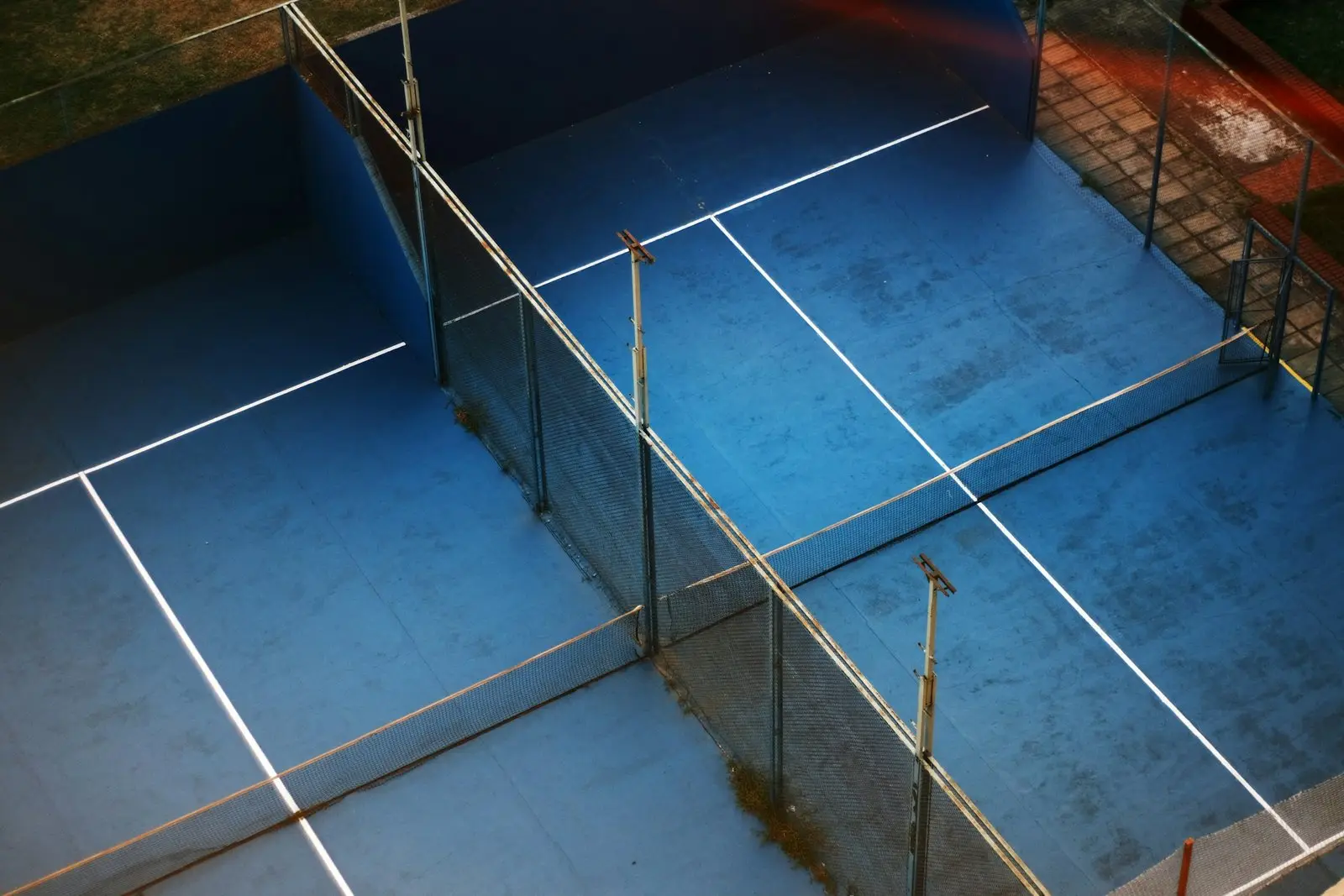 Rooftop padel court with a blue surface, glass back walls and mesh sides